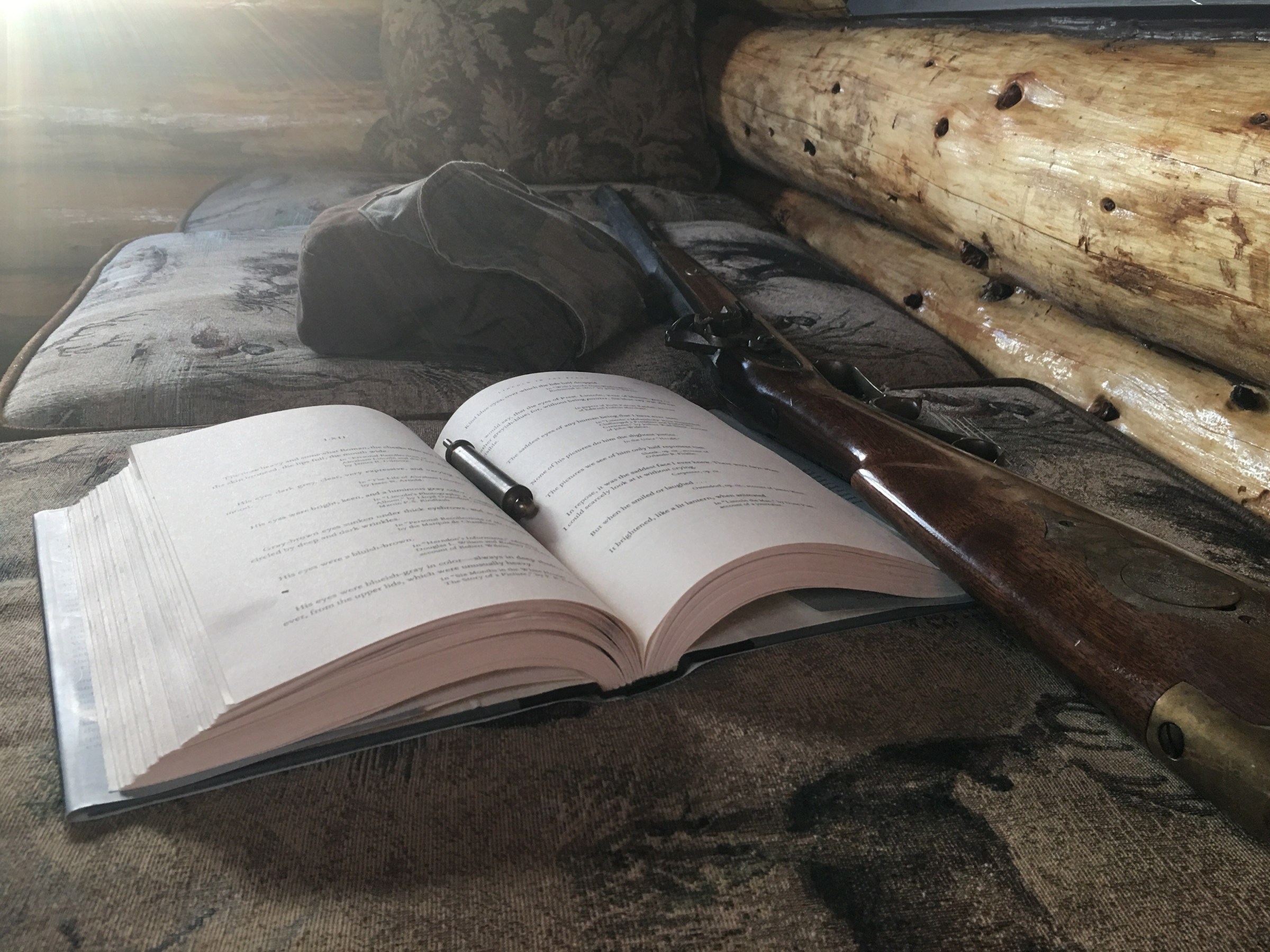 A book lies open next to a muzzleloader with wooden stock